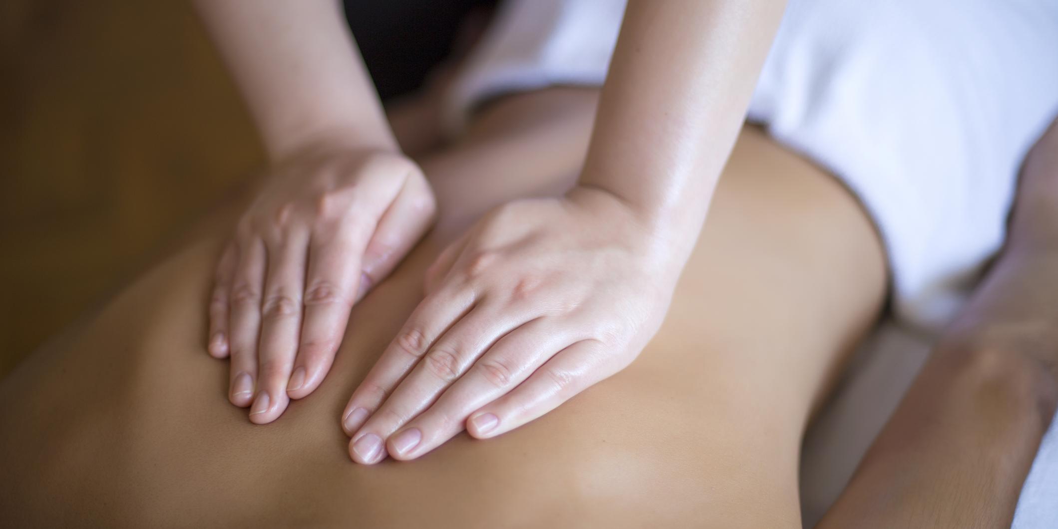 massage therapist hands on someone's back